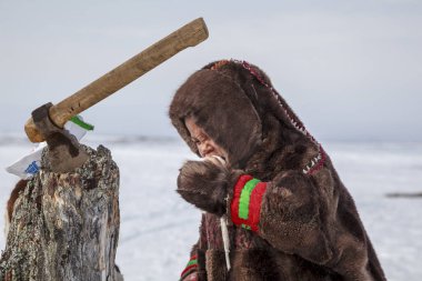 Nadym, Rusya Federasyonu - 27 Nisan 2018: tundra, açık alan, soğuk kış hava, Ulusal giysiler içinde çocuklar yardım Papa'nın yakacak odun, editoryal doğrayın