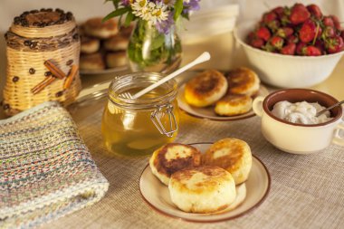 Kahvaltıda peynirli büyük bir tabak, süzme peynirli krep, taze çilekli krep ve papatya çiçekli çilek.
