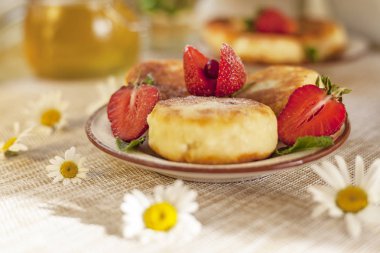 Kahvaltıda peynirli büyük bir tabak, süzme peynirli krep, taze çilekli krep ve papatya çiçekli çilek.