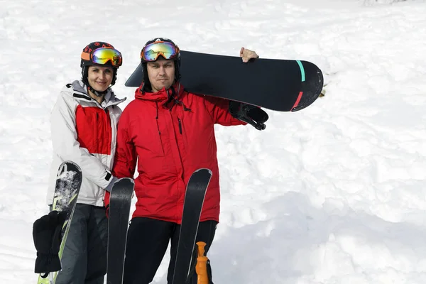 A young couple with skis in helmet and mask on the background of mountains; toned