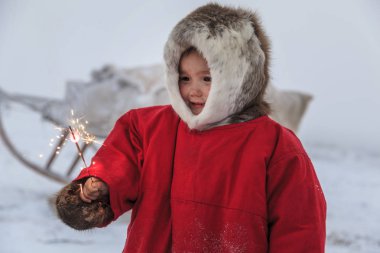 Tundra bir sakini, Far North, tundra, açık alan yerli sakinleri, çocuk kızakları üzerinde çocuk Ulusal giysiler içinde kırmızı giysili küçük kızı binmek