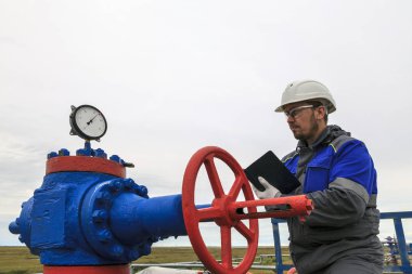 Gaz operatörü, operatör doğalgazı el koyuyor. Santral teknisyeni, üretim gazı, bir gaz kuyusu teknoloji modunda çalışıyor ve bir gaz kuyusunun çalışmasını izliyor.. 