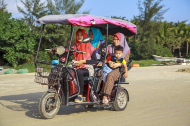 Çin, Hainan Adası, Sanya bay - 2 Aralık 2018: defne, Çince üç tekerlekli bisiklet elektrik moped Sanya, Çin insanlar plajda bir şehir, editoryal elektrikli bir üç tekerlekli bisiklet üzerinde