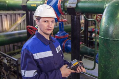 Enerji Mühendisi bir termal görüntücün boru hattındaki ağların sıcaklığını kontrol eder