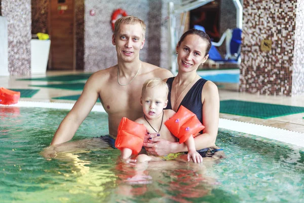 happy family relaxing in the spa center with a child swims in th