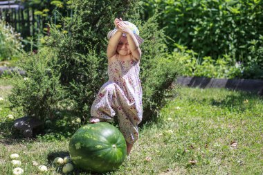 Yaz, küçük kız büyük bir karpuz üzerinde oturuyor