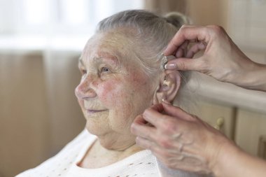 bir hemşire yardımcı olur bir 90 yıl eski Büyükanne eklemek bir işitme cihazı int