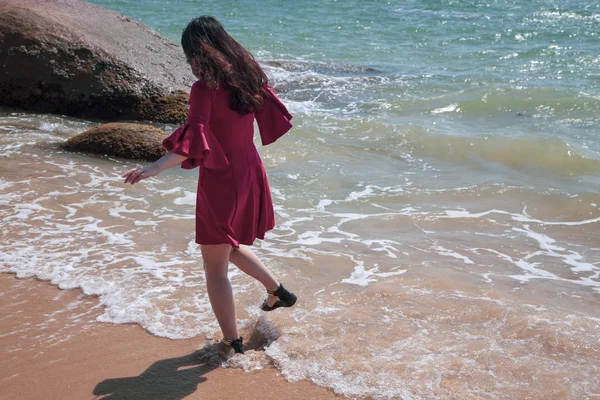 Belle femme se promène au bord de la mer, fille heureuse dans un dres rouge — Photo