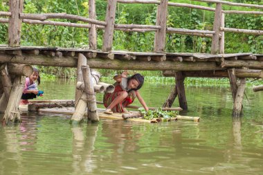 Kedi köyü, üç küçük kız gölde sala biniyor.