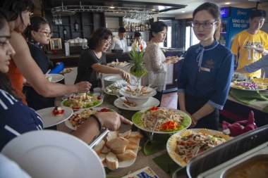 Halong 'da kireçtaşı dağları arasında seyahat eden turist gemileri.