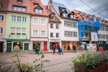 Bir Freiburg im Breisgau, Almanya - 31 Aralık 2017: bir kış gününde küçük bir Arnavut kaldırımlı tarihi şehir merkezinde tipik mimari evleriyle sokak üzerinde yürüyen insanlar