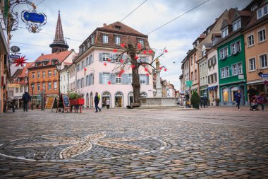 Bir Freiburg im Breisgau, Almanya - 31 Aralık 2017: bir kış gününde küçük bir Arnavut kaldırımlı tarihi şehir merkezinde tipik mimari evleriyle sokak üzerinde yürüyen insanlar