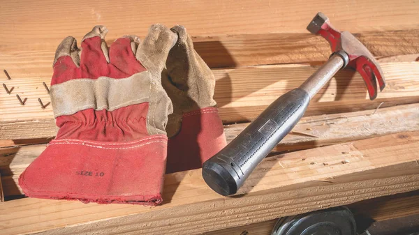 Viejo martillo oxidado y guantes de construcción colocados en tablero de madera —  Fotos de Stock