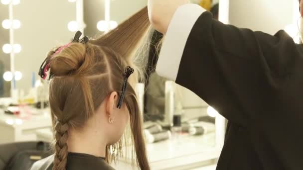 Haarstylist kammen onderdeel haren en sproeien water voor het snijden in de schoonheidssalon. Close-up van kapper maken van vrouwelijke kapsel in kapsalon. — Stockvideo