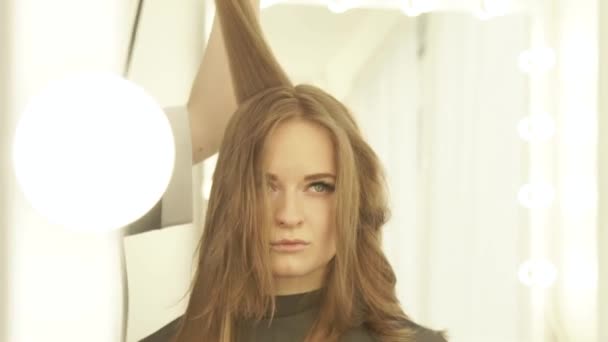 Fiatal nő hosszú haj szárító és hajkefe elülső tükör fodrászat a szárítás során. Közelről szárítás szárító nő haját fodrász és kozmetika fésű. — Stock videók
