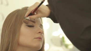 Sanatçı makyaj gözler güzellik Studio için kozmetik fırça kullanarak oluşturur. Genç kadın moda modeli için makyaj visagiste kadar kapatın.