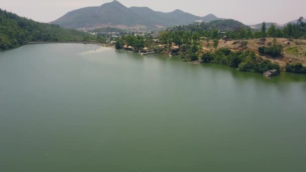 Luftaufnahme Fluss und Damm im Hintergrund grüne Hügel und Berge. Drohne fliegt über Fluss mit Staudamm und felsigem Ufer im Gebirge. — Stockvideo