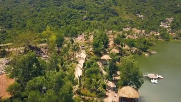 Aerial landscape bungalows on shore lake in water villa resort with beautiful mountain view. Beautiful river with stones among green mountains covered tropical forest. — Stock Video
