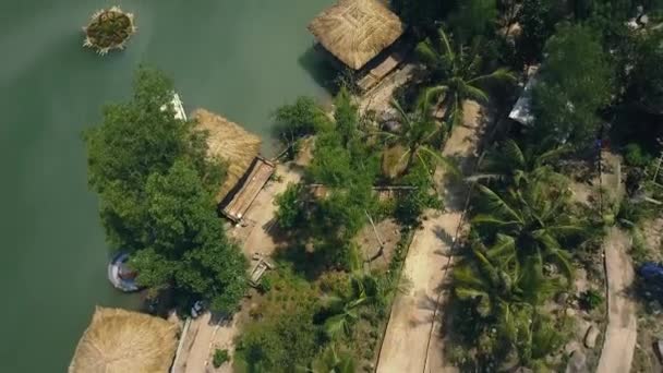 Bungalows and boats among exotic palms and trees on river bank Aerial view. Tropical landscape with flying drones houses among tropical plants for recreation. — Stock Video