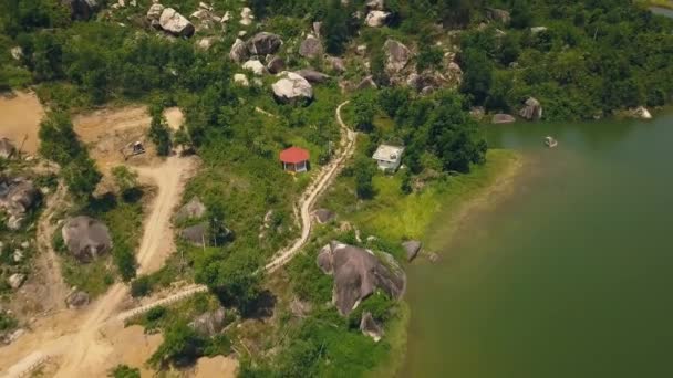 背景緑湖や大きな石の空中風景山道。湖の岸と緑飛行ドローンから岩の丘の眺め沿いの道路. — ストック動画