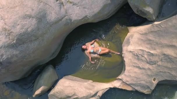 Donna sexy che si gode il bagno in vista aerea trasparente fiume acqua. Bella donna in bikini sdraiata nel fiume drone vista . — Video Stock