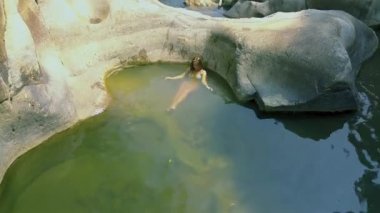 Temiz su nehirde yıkanan kadının. Mutlu kadın büyük kayaya yaslanmış nehir su rahatlatıcı. Havadan görünümü kız nehirde Yüzme.