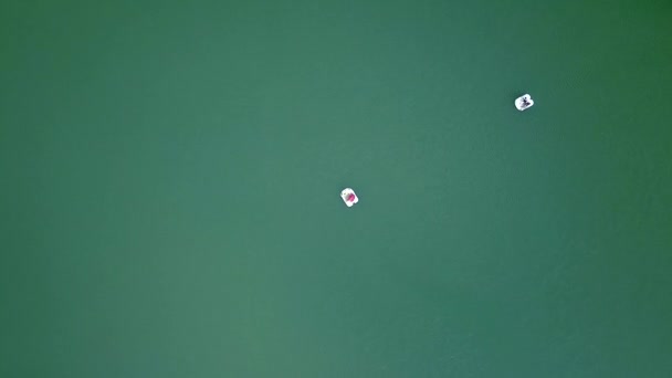 Люди катаються на катамарані на озерній воді. Вид з повітря на літаючих безпілотників, які плавають на катамарані на зеленій воді красиве озеро. Повітряний пейзаж . — стокове відео