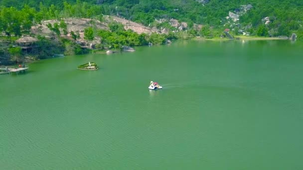 Antennenlandschafts-Katamaran, der auf einem See in den Bergen schwimmt. Drohnen sehen Menschen, die während ihres Sommerurlaubs auf einem Katamaran auf einem schönen See fahren. Sommeraktivität auf dem Wasserweg. — Stockvideo