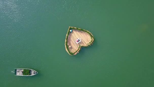 Rekaman perahu udara berenang di danau dengan hiasan tempat tidur bunga dalam bentuk hati. Orang-orang berayun di tempat tidur bunga mengambang di air hijau pemandangan danau drone yang indah . — Stok Video