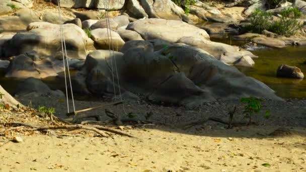 Huśtawka na brzegu rzeki kamieniste zwolnionym tempie. Drewniana Huśtawka, kołysanie na wybrzeżu na tle piękny krajobraz rzeka rocky. — Wideo stockowe