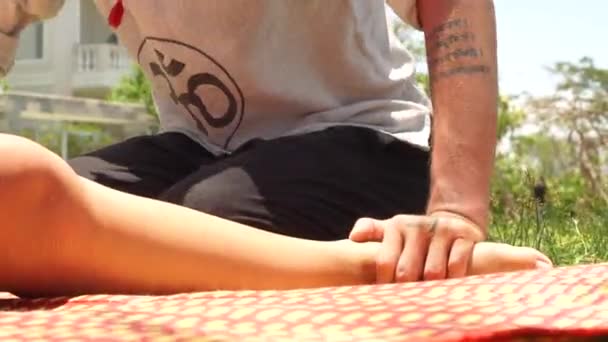 Ταϊλάνδης massagiste κάνοντας μασάζ στα πόδια με γυναίκα ξαπλωμένη στο γρασίδι. Επαγγελματική thai και γιόγκα μασάζ για χαλάρωση και ανάκτηση εξωτερική. Έννοια της παραδοσιακής και εναλλακτικής ιατρικής. — Αρχείο Βίντεο