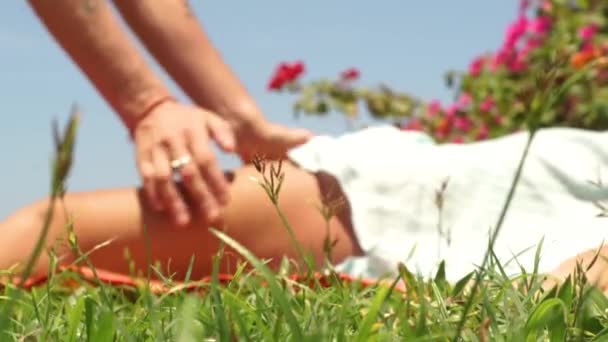 Thai massagiste making pressing massage to woman legs outdoor. Man massagist doing yoga massage for muscule relaxation. Traditional eastern massage for body lymph drainage. Healty lifestyle concept. — Stock Video
