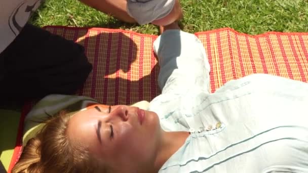 Mujer joven recibiendo masaje de manos al aire libre. Masajista haciendo masaje en estilo tailandés. Masaje de acupuntura yoga para el tratamiento de la salud corporal y espiritual. Medicina alternativa y tradicional india . — Vídeos de Stock