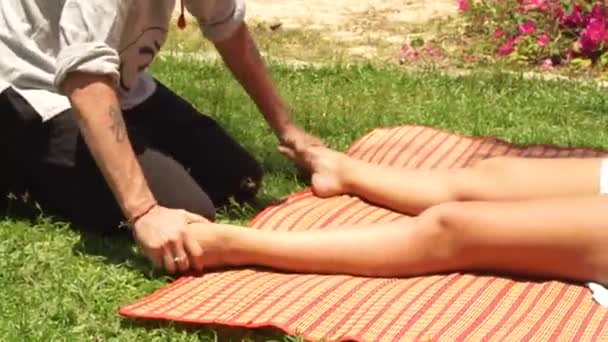 Masaje de pies en estilo tailandés al aire libre. Yoga masajista haciendo estiramiento masaje de pies a mujer para curación y recuperación corporal. Masaje tailandés y yoga en medicina oriental alternativa y tradicional . — Vídeos de Stock