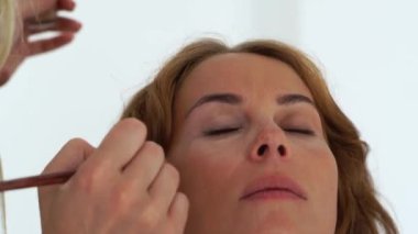 Makyaj sanatçısı Vakfı krem yüz makyaj modeli uygulanıyor. Güzellik stüdyosu genç kadın için profesyonel makyaj.