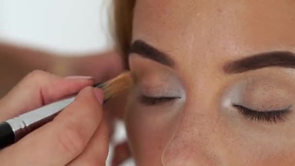 Primer plano visagiste utilizando cepillo cosmético para sombras de aplicación en el modelo de maquillaje de párpados. Maquillaje artista aplicar glamour maquillaje a la cara de mujer. Belleza y moda . — Vídeos de Stock