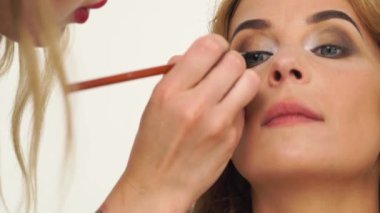 Visagiste resim glamour Oklar fırça için gözünüzü dört açın olun. Siyah göz kalemi göz kapağı akşam makyaj uygulayarak makyaj sanatçısı. Güzellik ve moda endüstrisi.