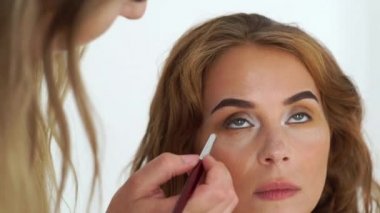 Makyaj sanatçı güzellik modeli ile çalışma ve akşam makyaj gözleri kozmetik fırça ile yapıyor. Güzellik Studio profesyonel kadın makyaj. Stil ve moda kavramı.
