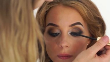 Sanatçı maskara kirpik üzerinde uygulama oluşturur. Yüz makyaj model uygulama maskara kirpik üzerinde. Şık gözler makyaj kapatın. Güzellik ve fashiom Sanayi.