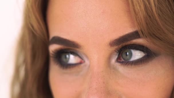 Närbild av kvinna med sotade ögon make up. Ansikte glamour kvinna med ljusa och perfekt makeup. Porträtt vacker kvinna med grå ögon tittar sida. — Stockvideo