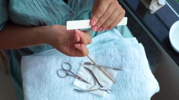 Mujer limar uñas con lima de uñas en fondo herramientas de manicura. Manicura casera y cuidado de uñas. Cerca de la mujer haciéndose manicura en casa . — Vídeos de Stock