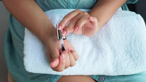 Mulher aplicando esmalte de base enquanto manicure em casa. Mulher fazendo manicure decorativo usando laca de unhas em casa. Conceito de manicure e cuidado em casa . — Vídeo de Stock
