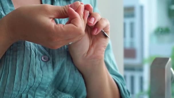 Mujer mujer usando herramientas de manicura para el cuidado de uñas. Una mujer cercana haciéndose la manicura en casa. Manicura casera y cuidado de uñas . — Vídeo de stock