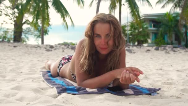 Retrato de mujer joven tomando el sol en la playa de arena durante las vacaciones de verano. Hermosa mujer bronceándose en la playa del mar . — Vídeos de Stock