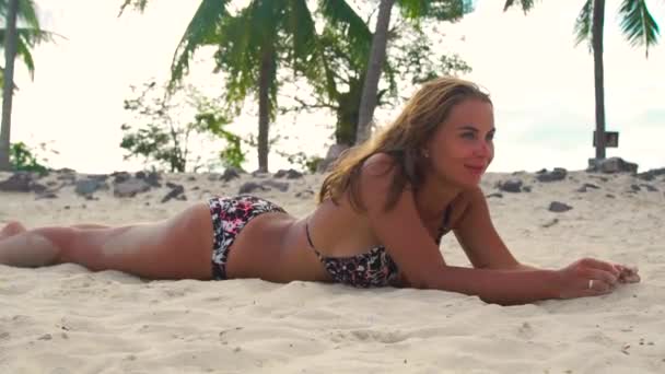 Leende kvinna liggande på sandstranden och sola medan sommarsemester. Lycklig kvinna sun tanning på sommar strand på sand och palm träd bakgrund. — Stockvideo