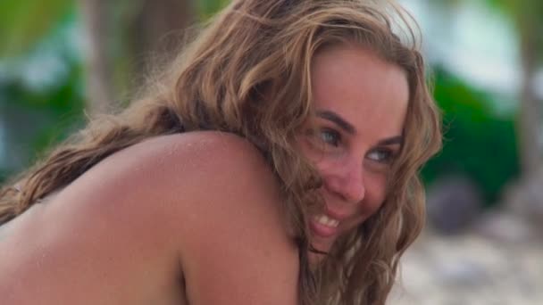 Mujer retrato riendo mujer mientras broncea en la playa de verano. De cerca mujer feliz en bikini sonriendo y mirando a la cámara . — Vídeo de stock