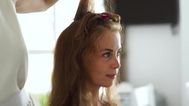 Kapper maken bouffant haar met behulp van de kam en haarspray voor het maken van kapsel naar mooie vrouw in de schoonheidssalon. Haarstylist volume kapsel doen en bevestiging met haarlak. — Stockvideo