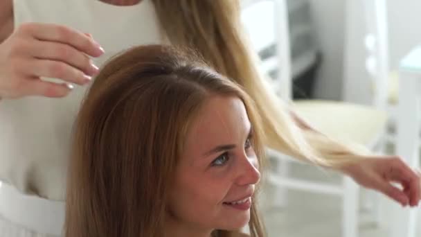 Peluquería haciendo peinado con bouffant y ondulación para mujer joven con el pelo largo. Peluquero haciendo peinado para mujer de pelo largo en peluquería . — Vídeos de Stock