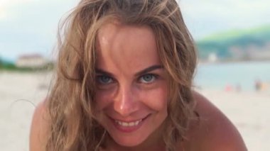 Portre çiller cilt ve kumral plaj arka plan ile güzel bir kadın. Gülümseyen ve kameraya bakarak kıvırcık saçlı yüzü çilli kadın kapatmak.