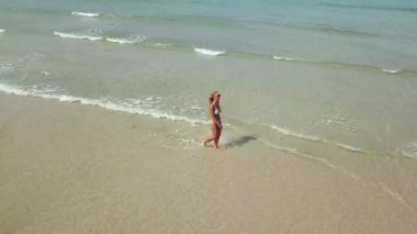 Genç kadın seksi bikini şeffaf su hava Oda yaz sahilde yürüyüş. Turkuaz deniz suda dron görünümü mutlu kadın.